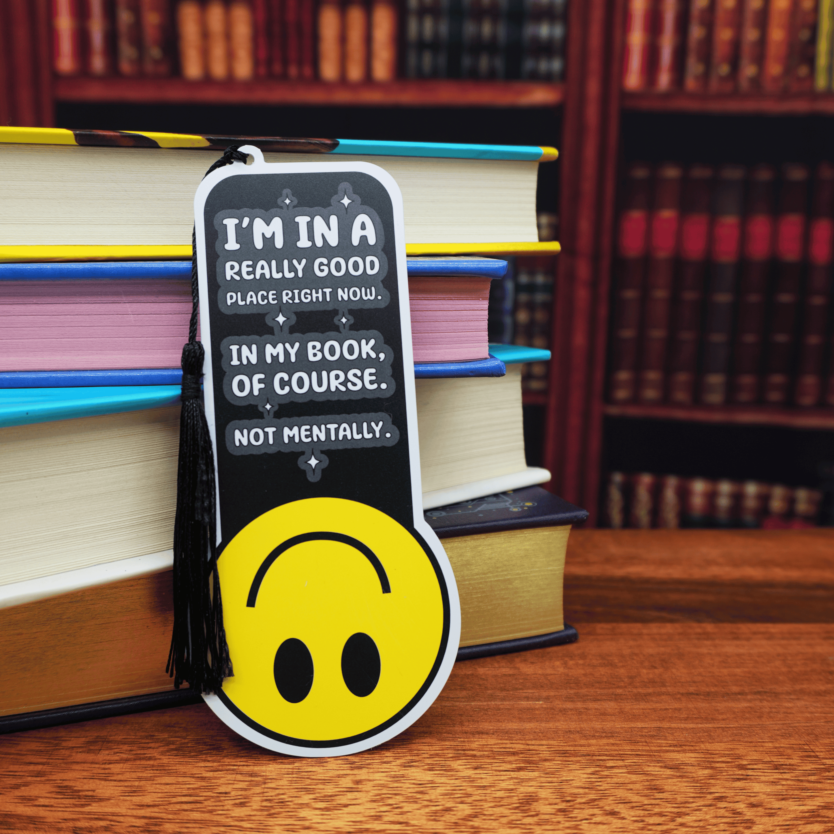 Bookmark with smiley face design and humorous text on a stack of books.