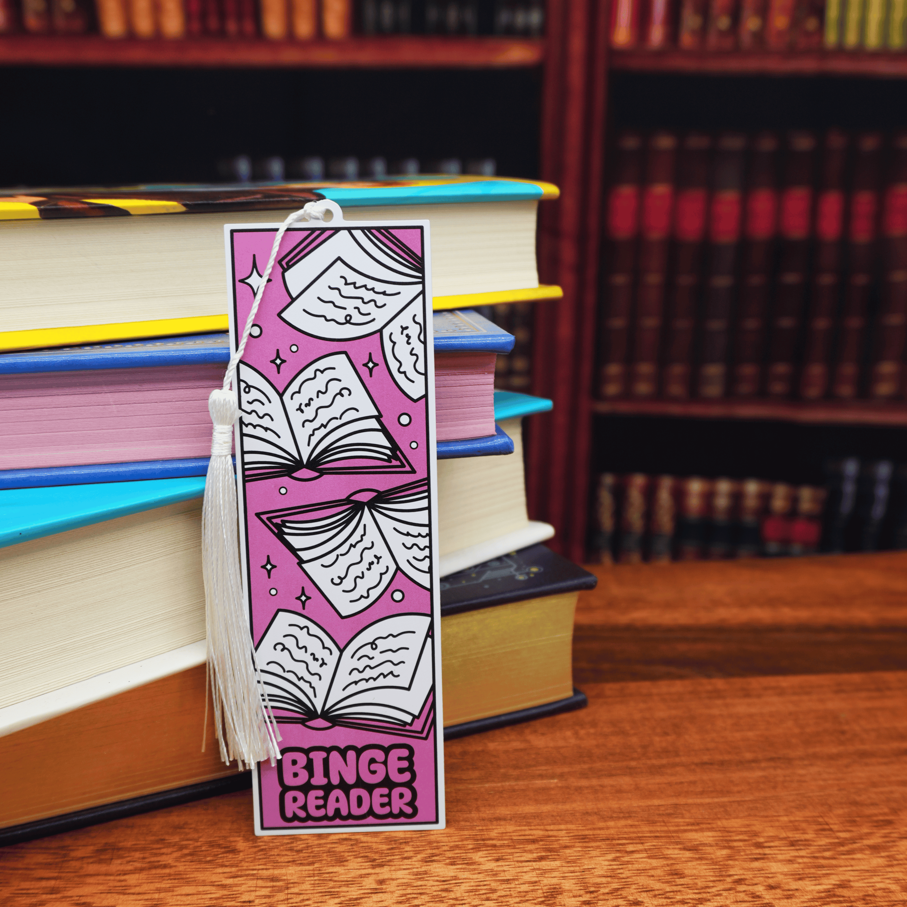Bookmark with 'Binge Reader' design on a stack of books in a library setting