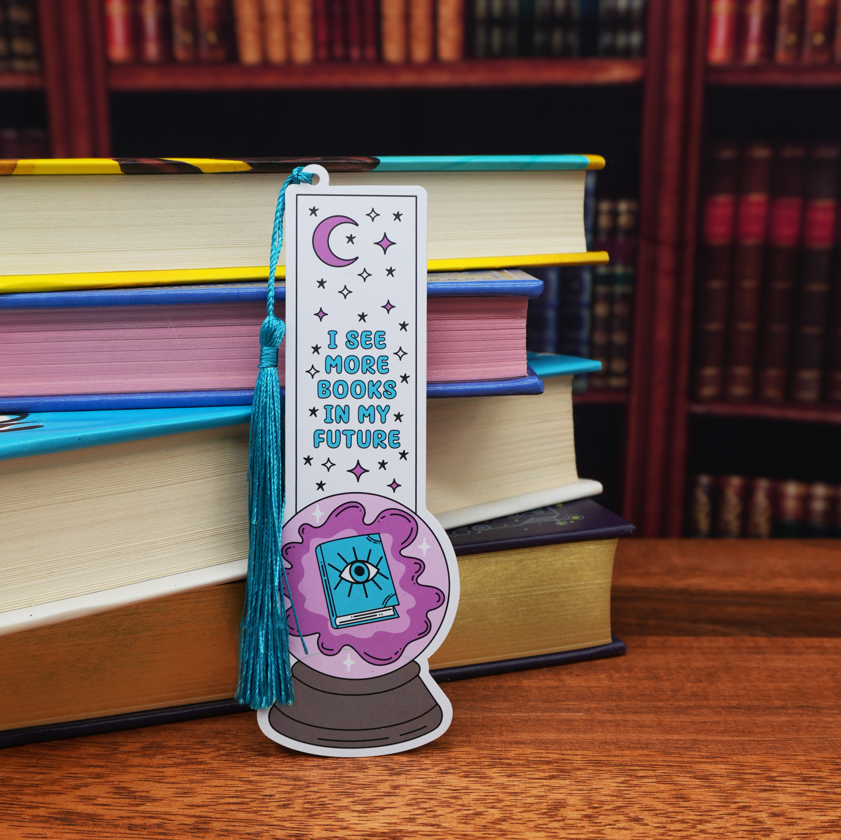 Bookmark with tarot card design and text 'I see more books in my future' on a stack of books.