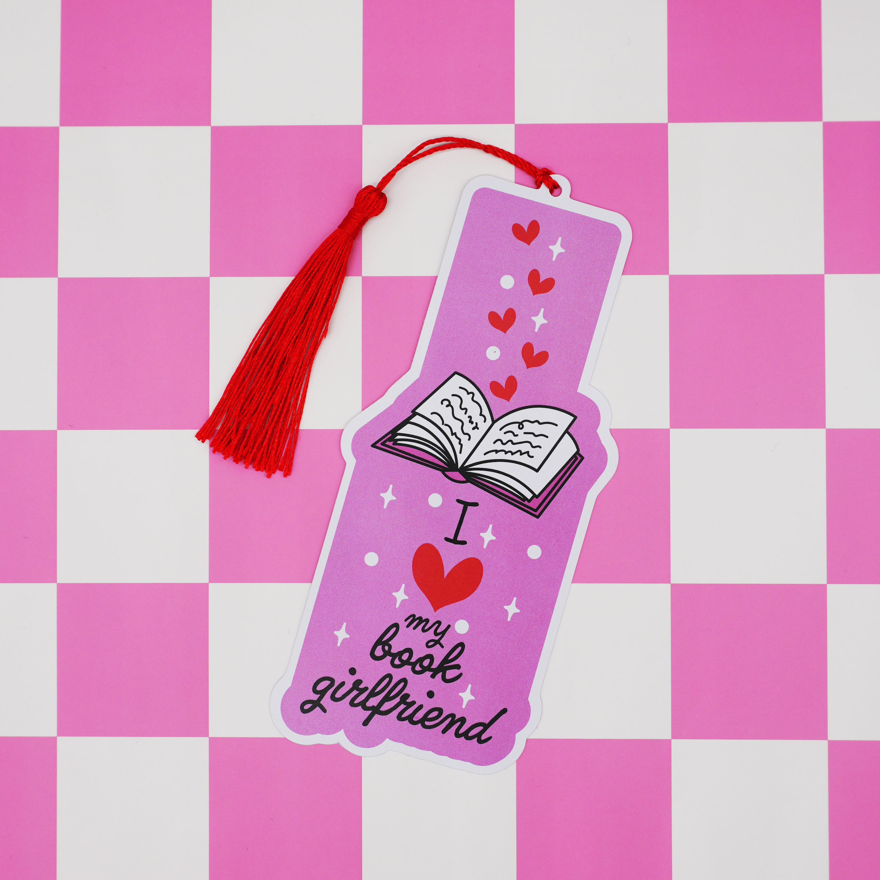 Pink bookmark with tassel on a pink and white checkered background