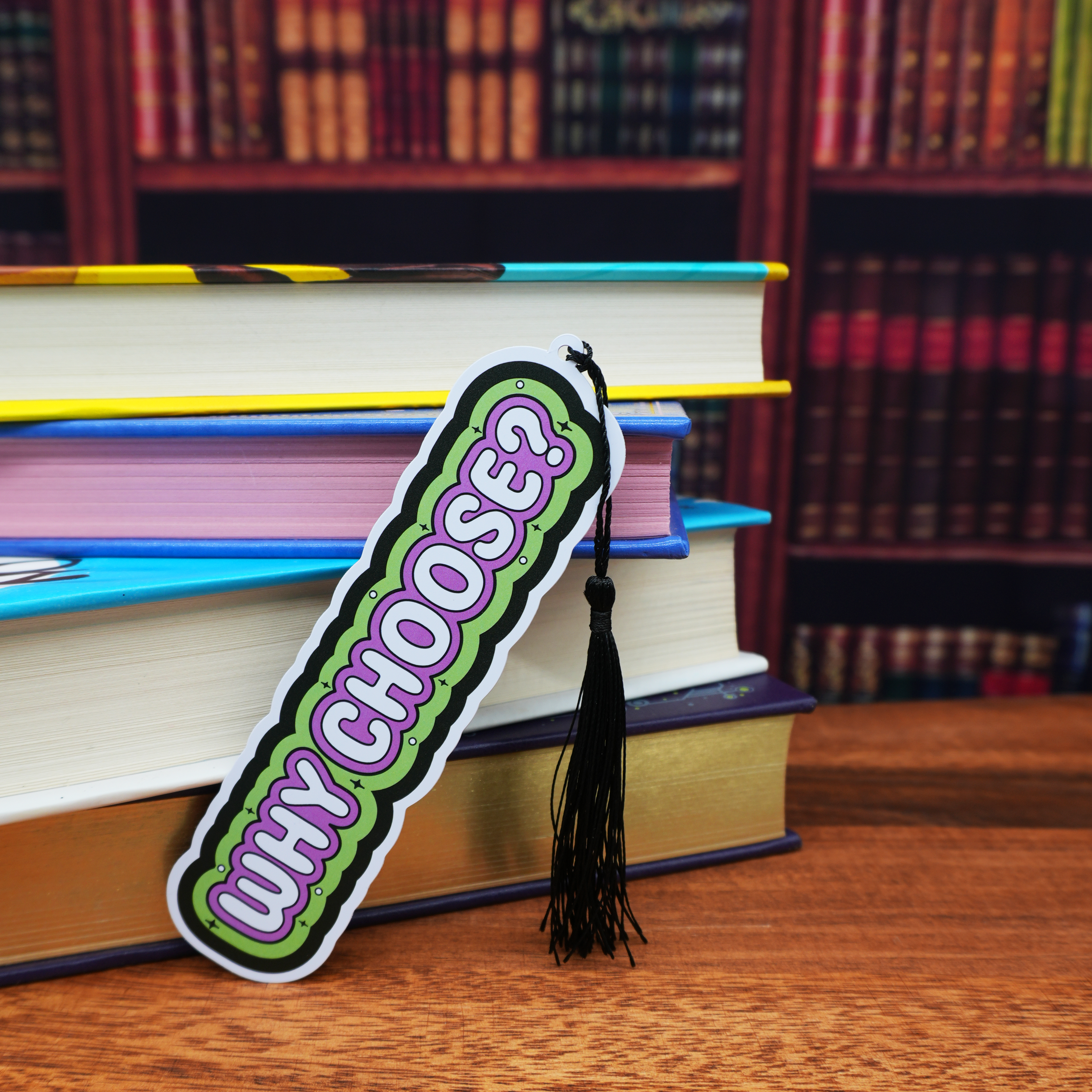 Bookmark with 'WHY CHOOSE?' text on a stack of books in a library setting