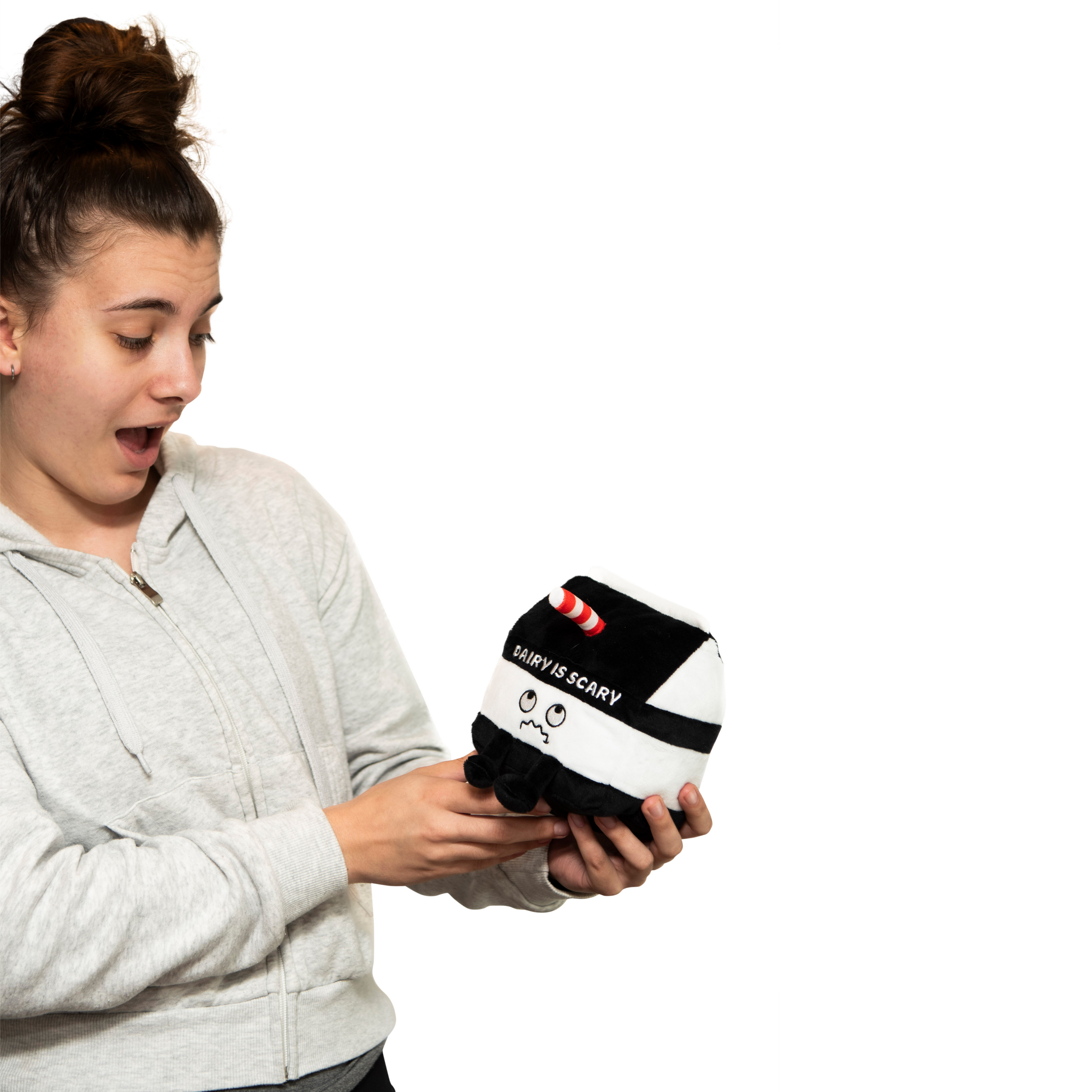 A woman holding a plush designed to look like a milk carton with a distressed face and the text 'DAIRY IS SCARY' on front.