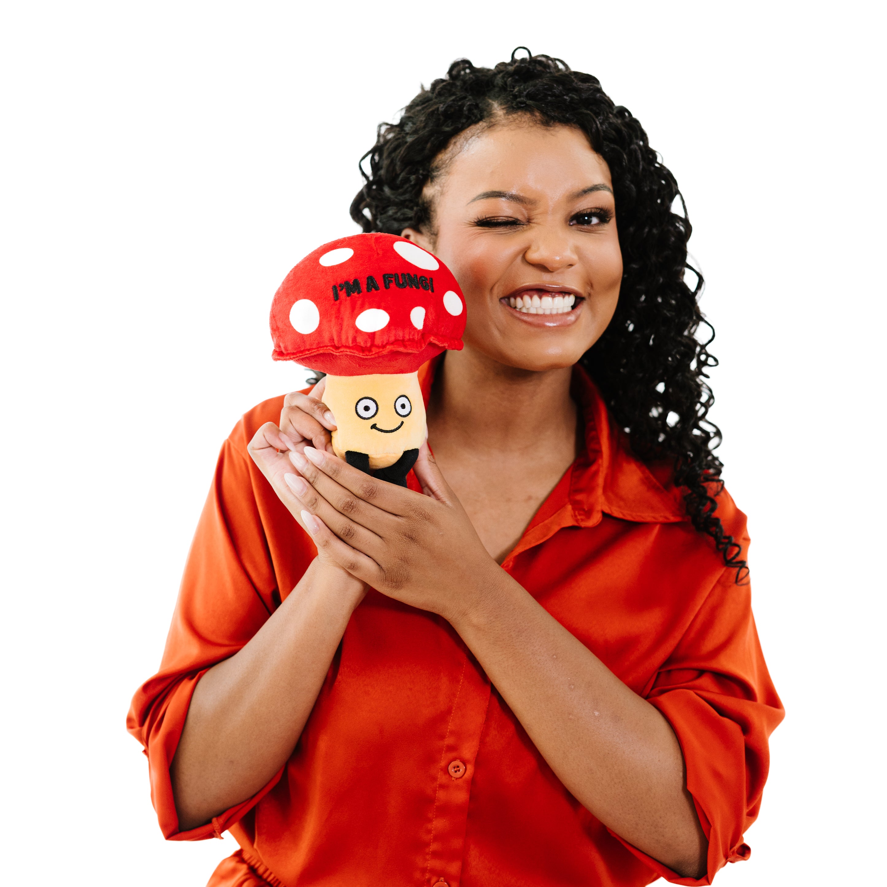 A woman holding a plush shaped like a red and yellow mushroom with a smiling face and the text 'I'M A FUNGI' on its cap.