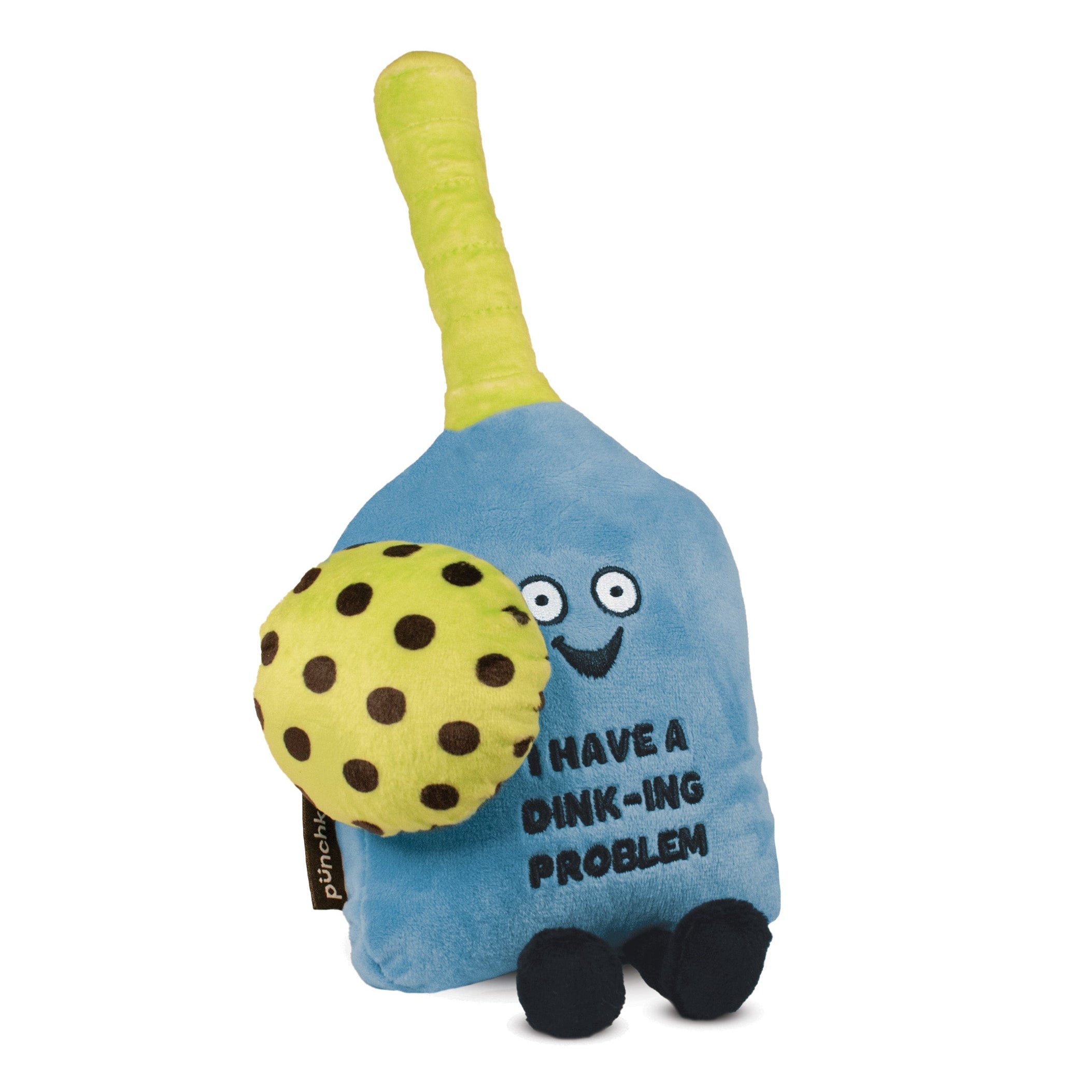 A plush pickleball paddle with a blue body, green handle, a green ball with black dots, and 'I have a dink-ing problem' written on it. It has a smiling face and dangly legs.