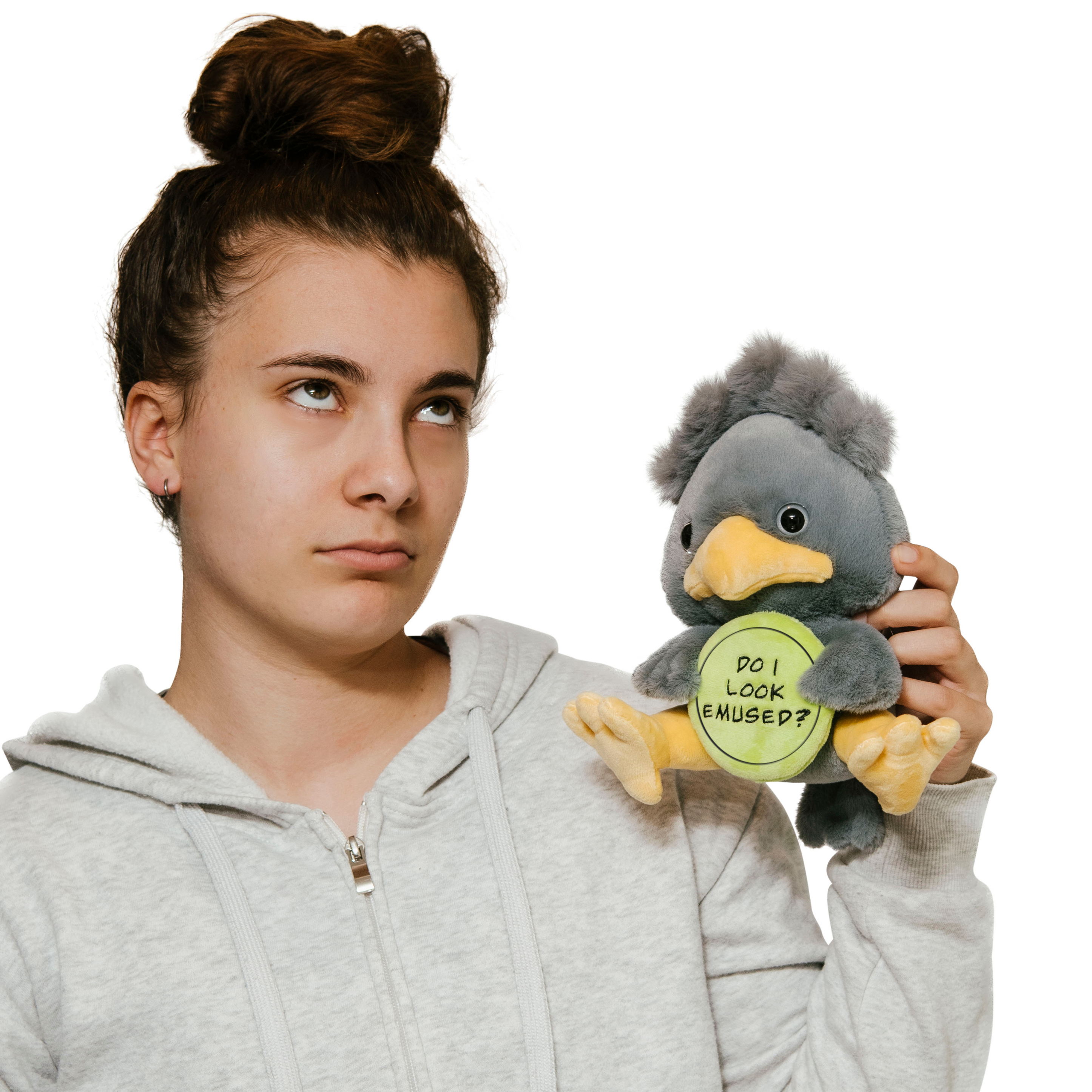 A woman holding a plush depicting a gray emu holding a green sign with the text 'DO I LOOK EMUSED?'