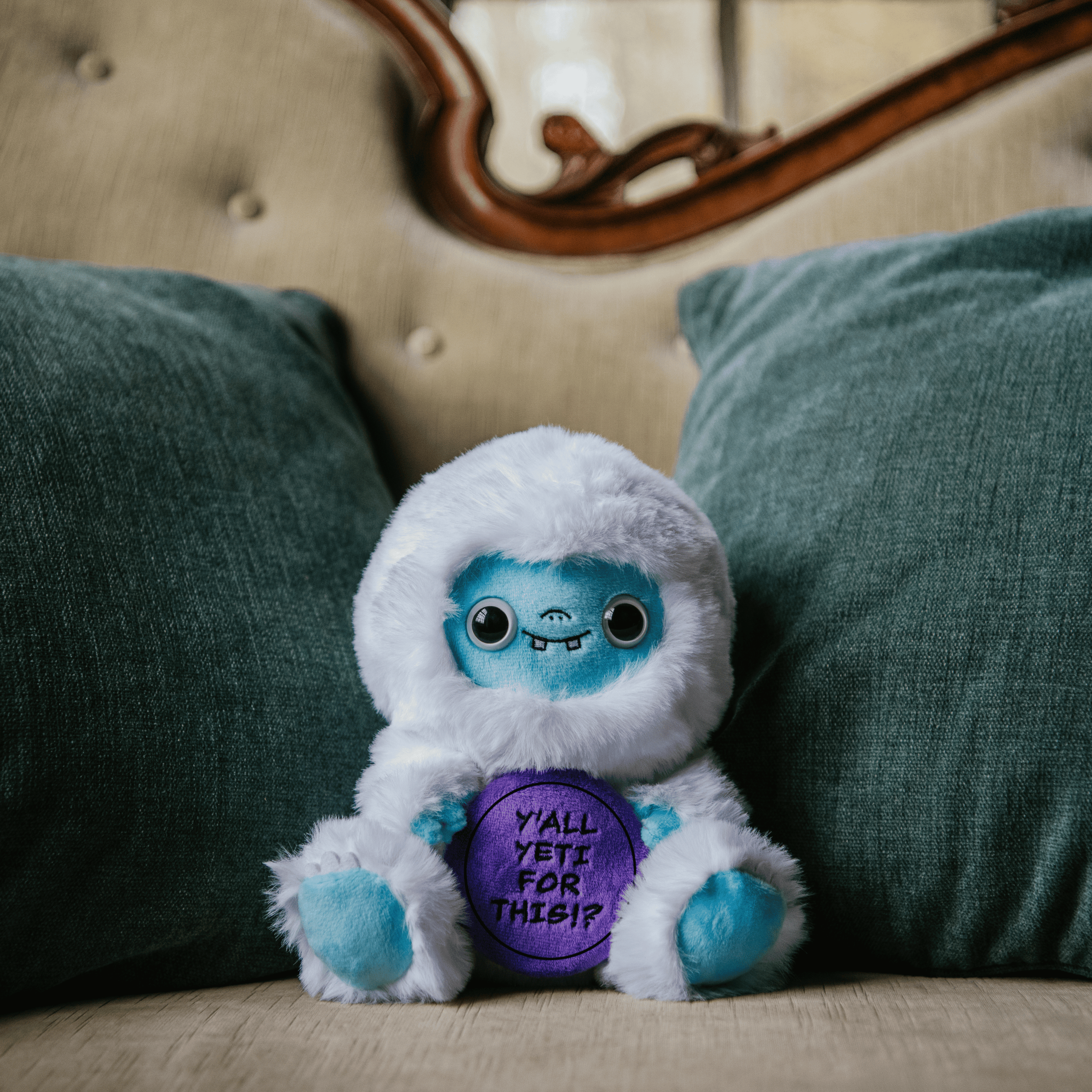 A plush depicting a yeti with white with text that reads, 'Y'all yeti for this!?' placed on a couch.