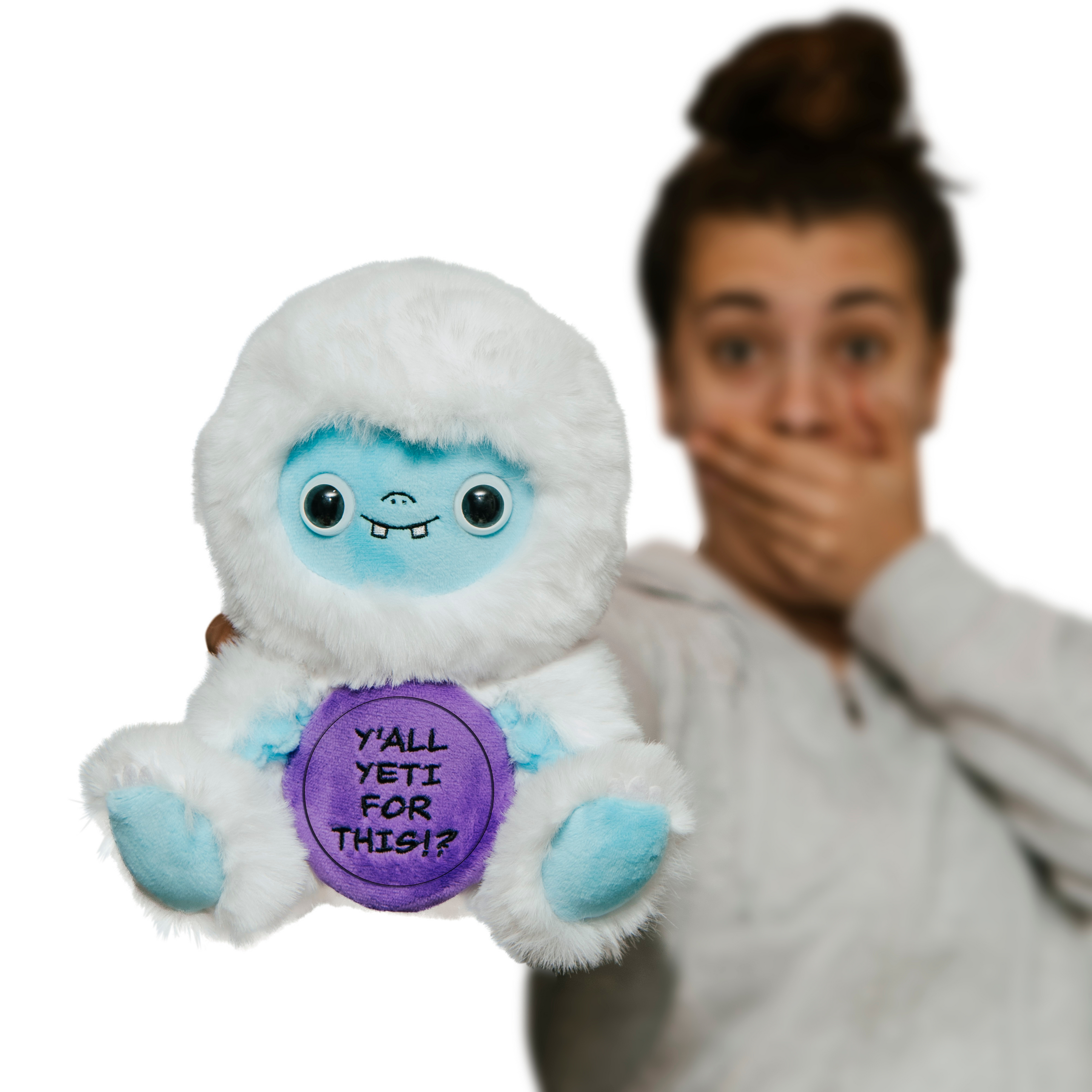 A woman holding a plush depicting a yeti holding a purple sign with text that reads, 'Y'all yeti for this!?'