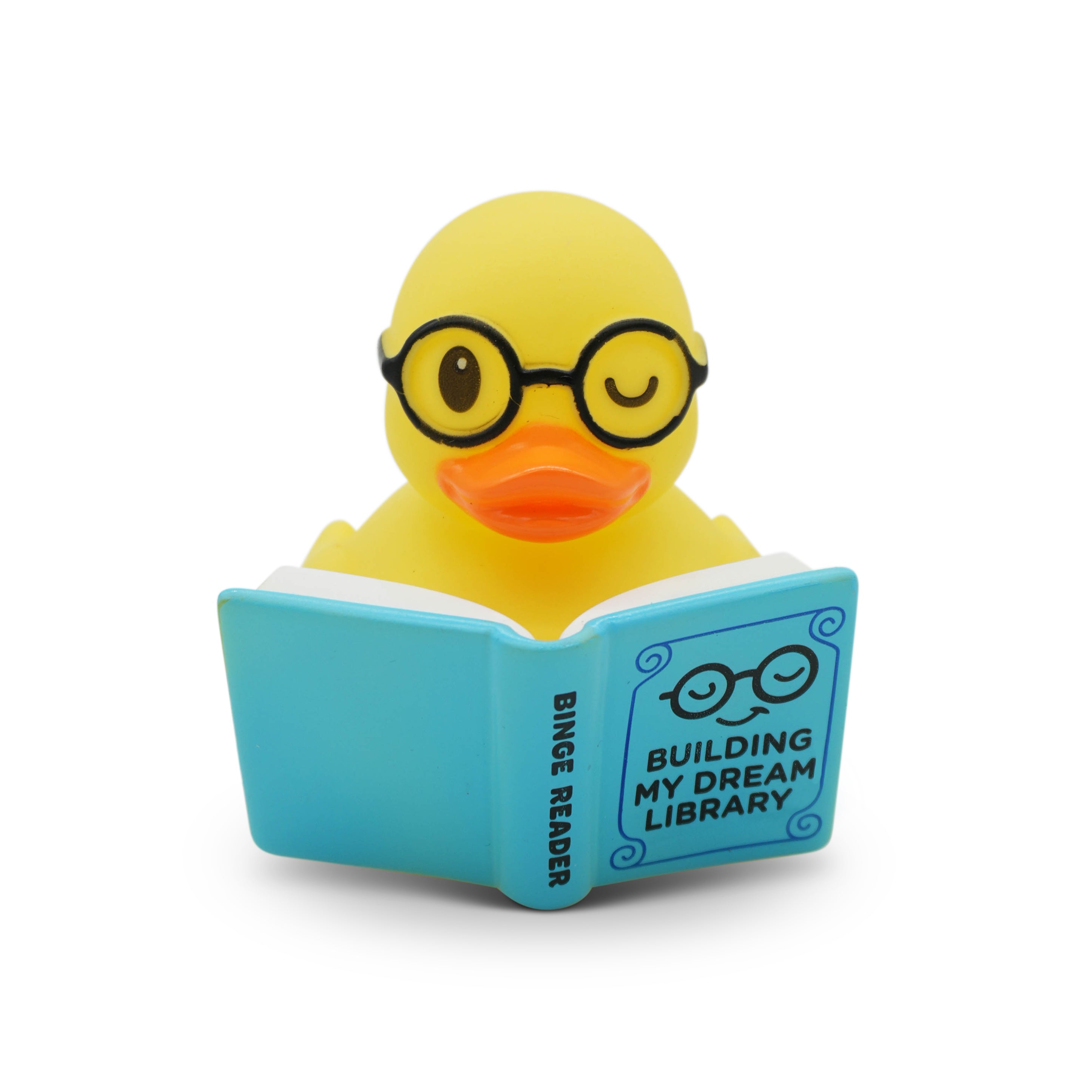 Yellow rubber duck wearing glasses and reading a book titled 'Building My Dream Library' on a white background