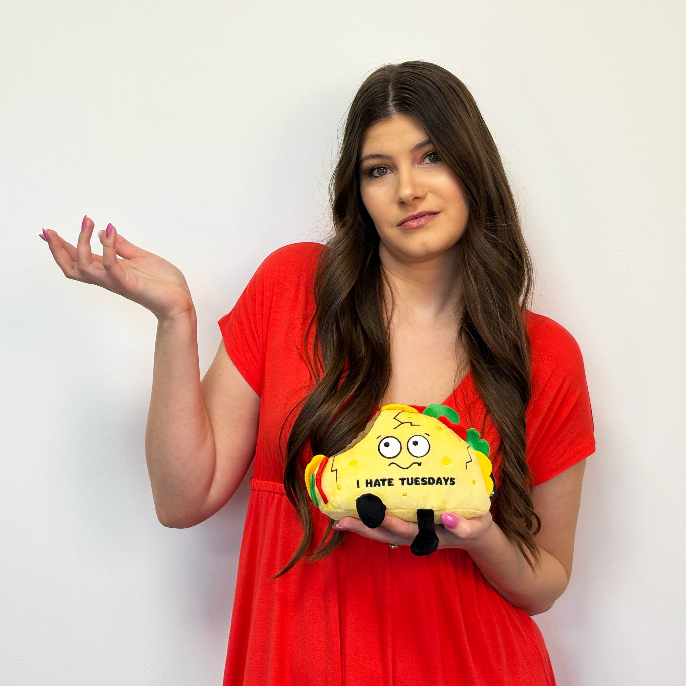 Brunette woman holding a plush taco with the text 'I HATE TUESDAYS' embroidered on it. 
