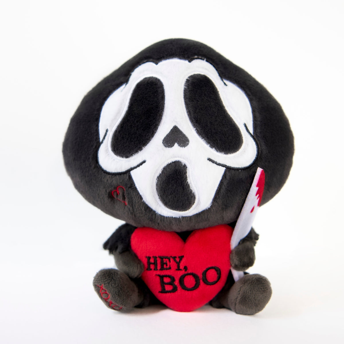 A plush toy depicting a ghost face killer with a heart nose holding a knife and a red heart-shaped sign with the text 'HEY, BOO'.