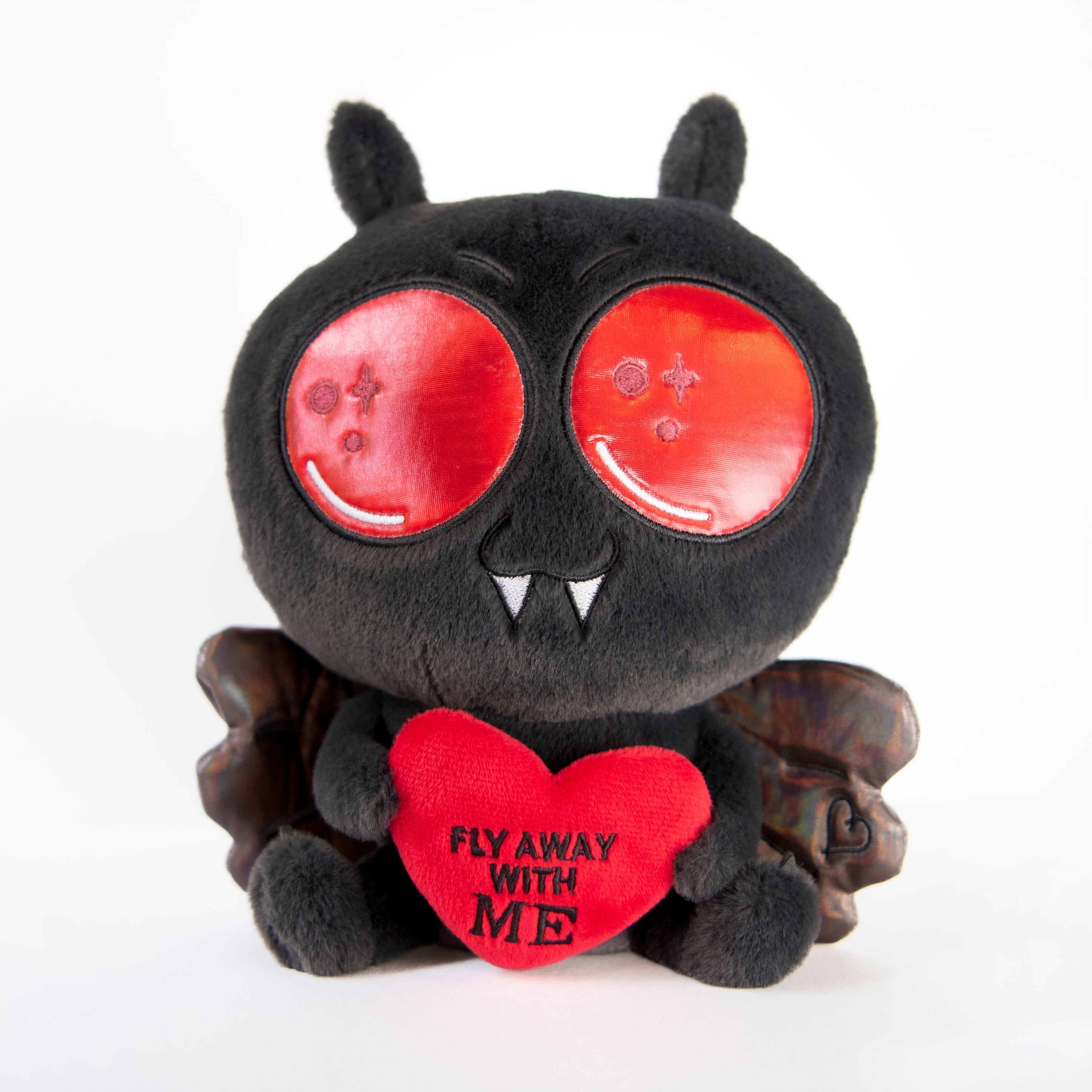 A plush of the Mothman featuring 3D metallic wings, holding a red heart that says 'fly away with me', with a smiling face and big eyes.