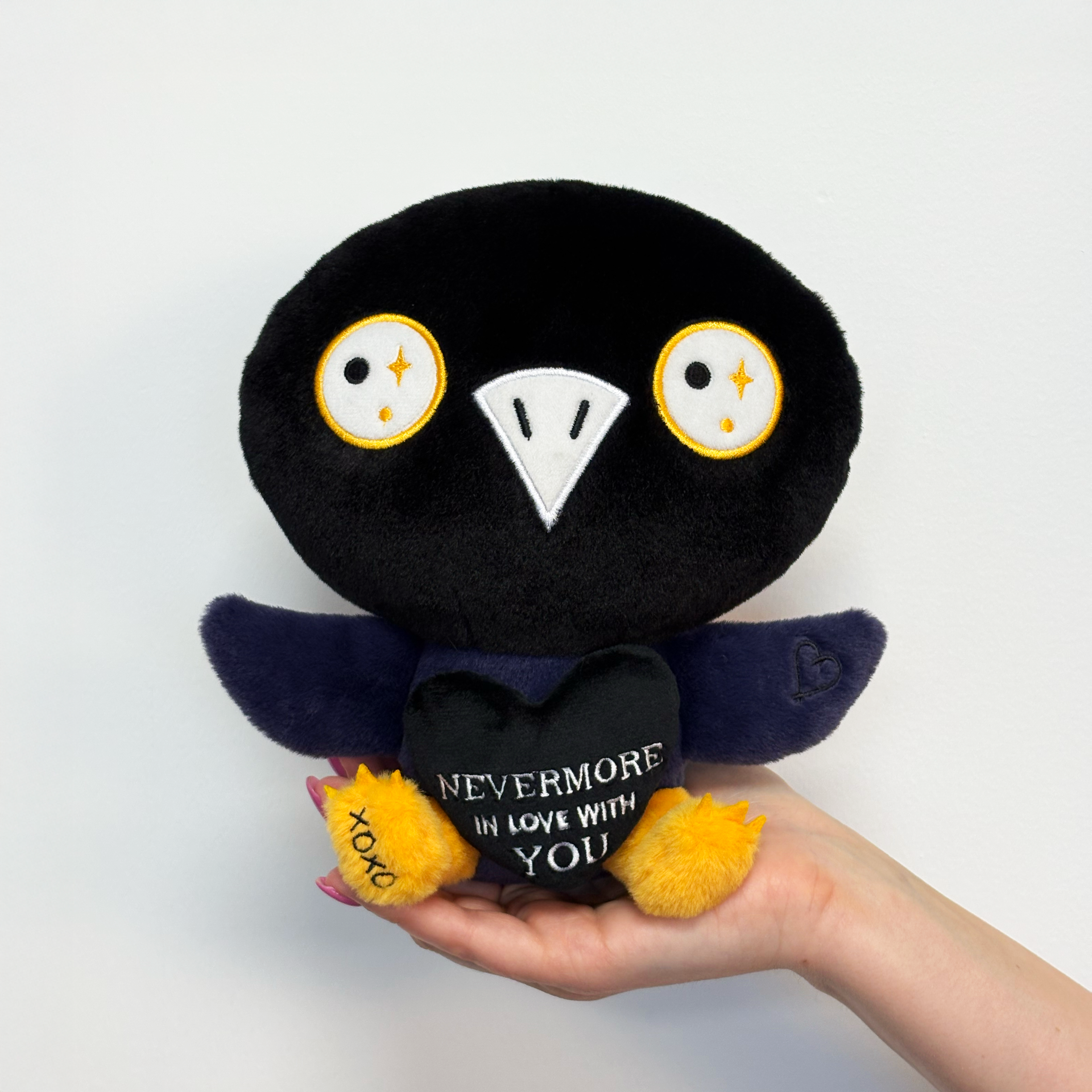 Hand holding raven plush toy that says nevermore in love with you 