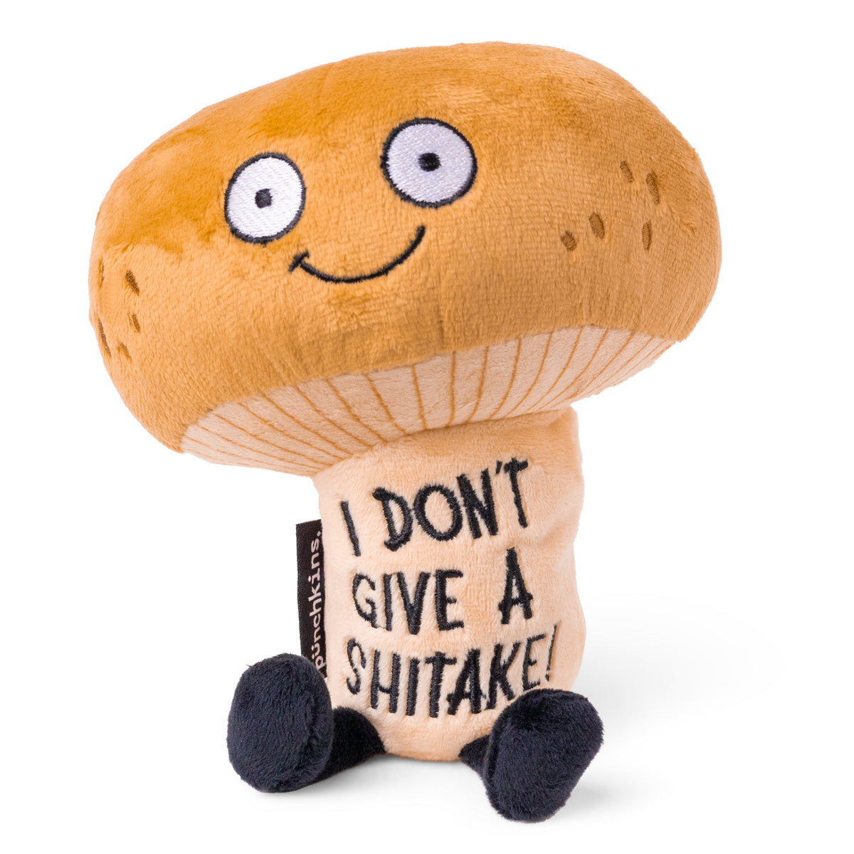 A plush toy shaped like a mushroom with a smiling face and a text tag that reads 'I DON'T GIVE A SHITAKE'.