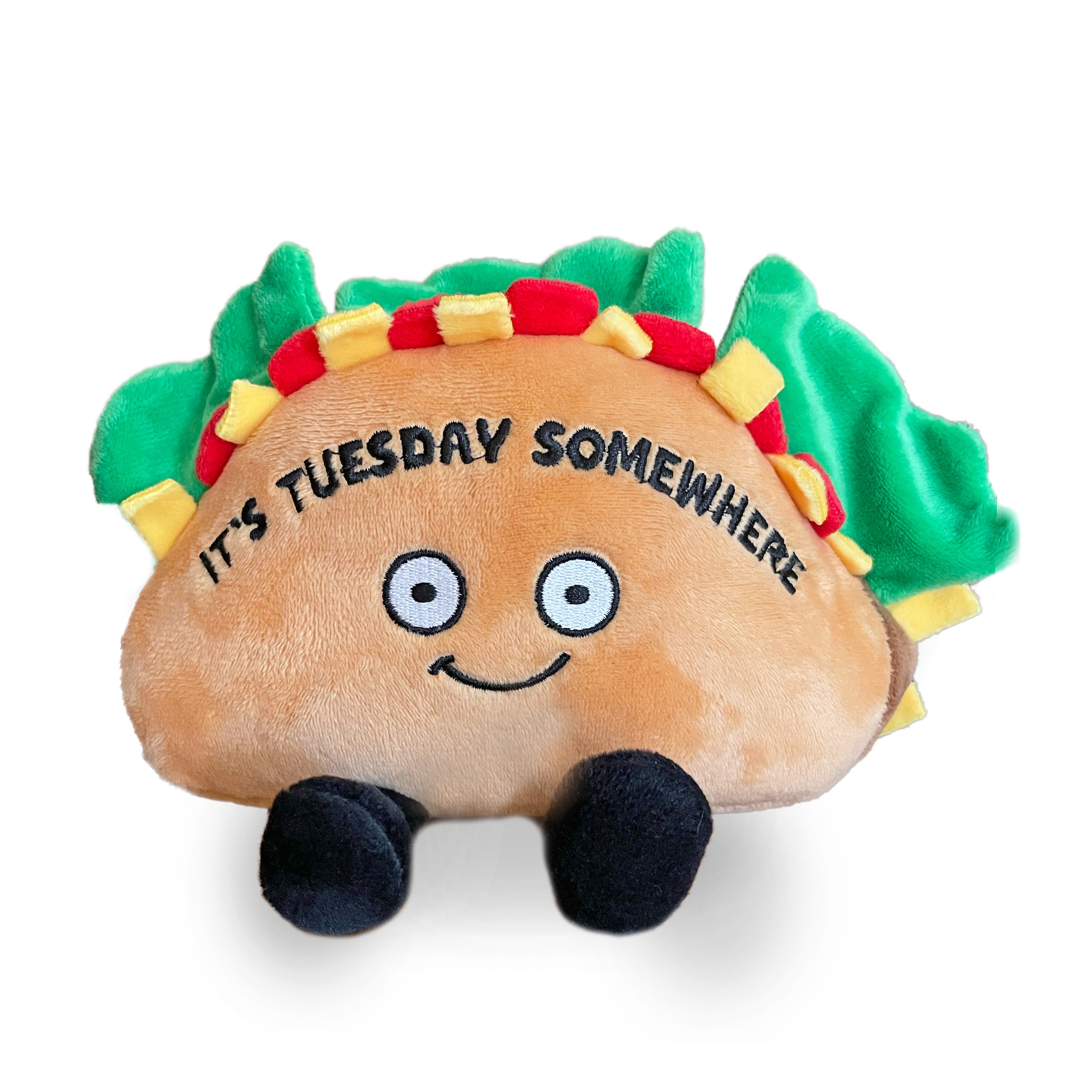 A plush shaped like a taco with a smiling face, green lettuce leaves, and the text 'IT'S TUESDAY SOMEWHERE' on the shell.